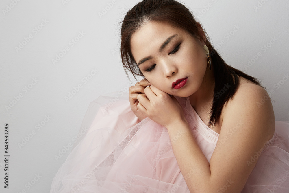 Asian attractive woman with dark long hair posing over white background. Beauty and feminity concept. Space for text. Asian attractive woman with dark long hair posing over white background. Beauty and feminity concept. Space for text.