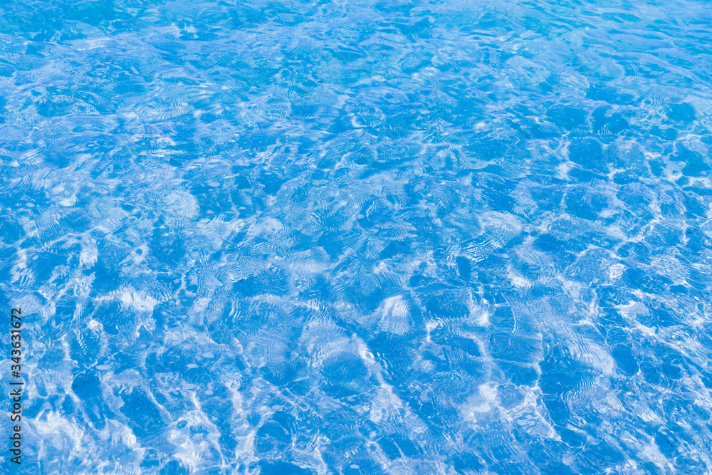 Blue clear water in the pool. Texture of water surface. Overhead view, Swimming pool bottom caustics ripple and flow with waves background.