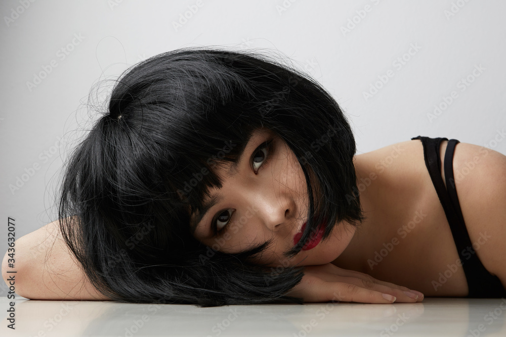 Photo of serious asian woman with dark hair, looks straightly at camera, poses over white background. Beauty concept Photo of serious asian woman with dark hair, looks straightly at camera, poses over white background. Beauty concept