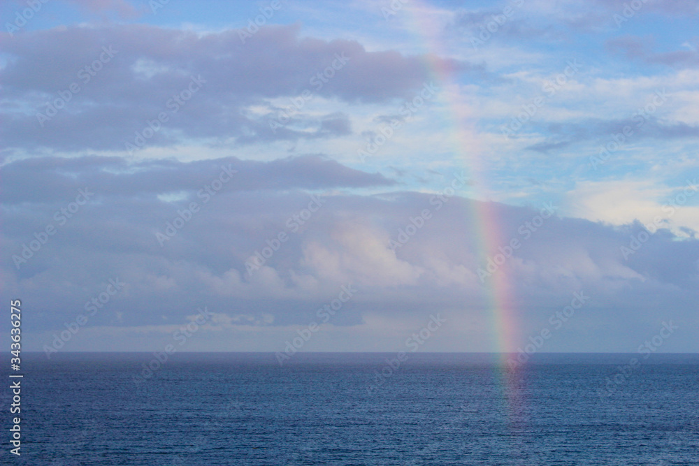 Rainbow over the ocean on a cloudy day. 