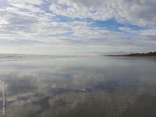 Reflections of a cloudy sky on a calm beach landscape. Waimairi Beach, Christchurch.