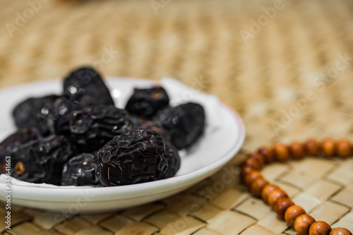 Ramadan food and drink in rural area or countryside concept. Muslim fasting. Dates fruits, prayer beads, drinking water on traditional mat.