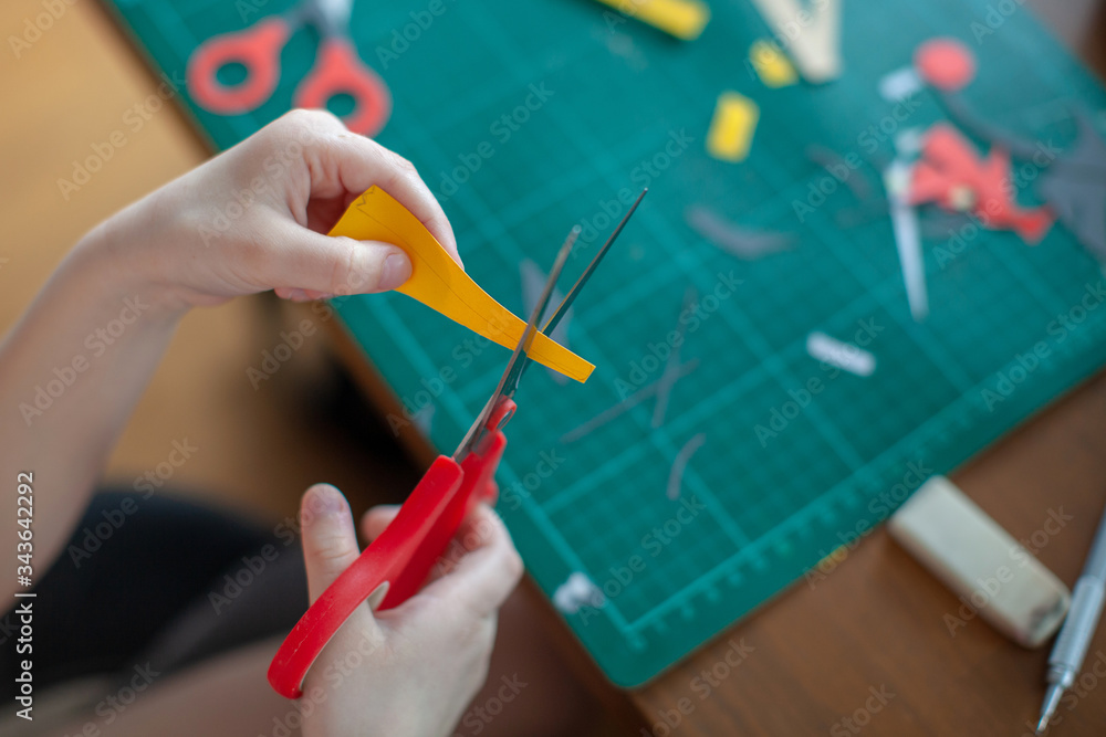 A seven-year-old girl cuts out with a scissors yellow paper. Craft with kids. A seven-year-old girl cuts out with a scissors yellow paper. Craft with kids.