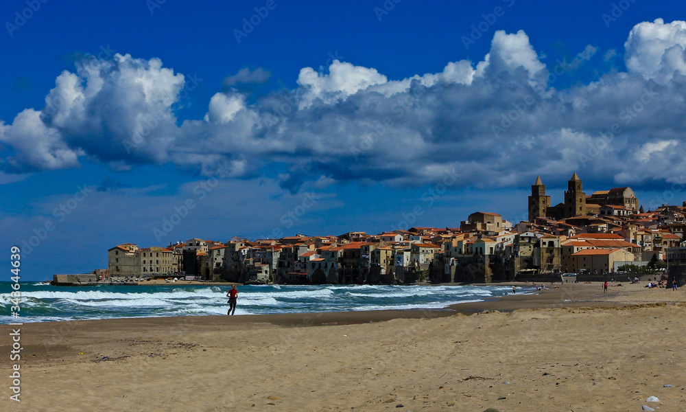 the beach of Cefalu leading to its old town, Sicily. Its a sunny spring day