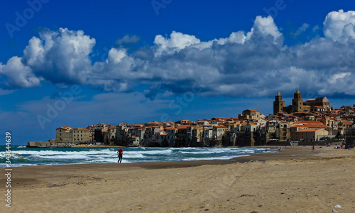 the beach of Cefalu leading to its old town, Sicily. Its a sunny spring day