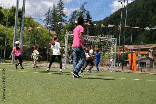 little children play football under the supervision of an animator. Children playing Football at park. Child Childhood Children Happiness Togetherness Concept