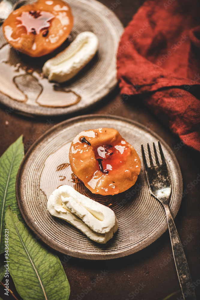 Turkish traditional dessert with sweet quince boiled in sugar syrup, spices and heavy cream Kaymak on ceramic plates over rusty brown table background, selective focus. Turkish national cuisine Turkish traditional dessert with sweet quince boiled in sugar syrup, spices and heavy cream Kaymak on ceramic plates over rusty brown table background, selective focus. Turkish national cuisine