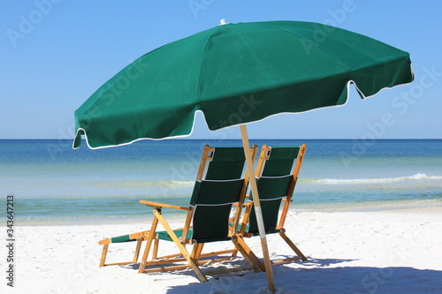 Two chairs and green umbrella on white sand beach