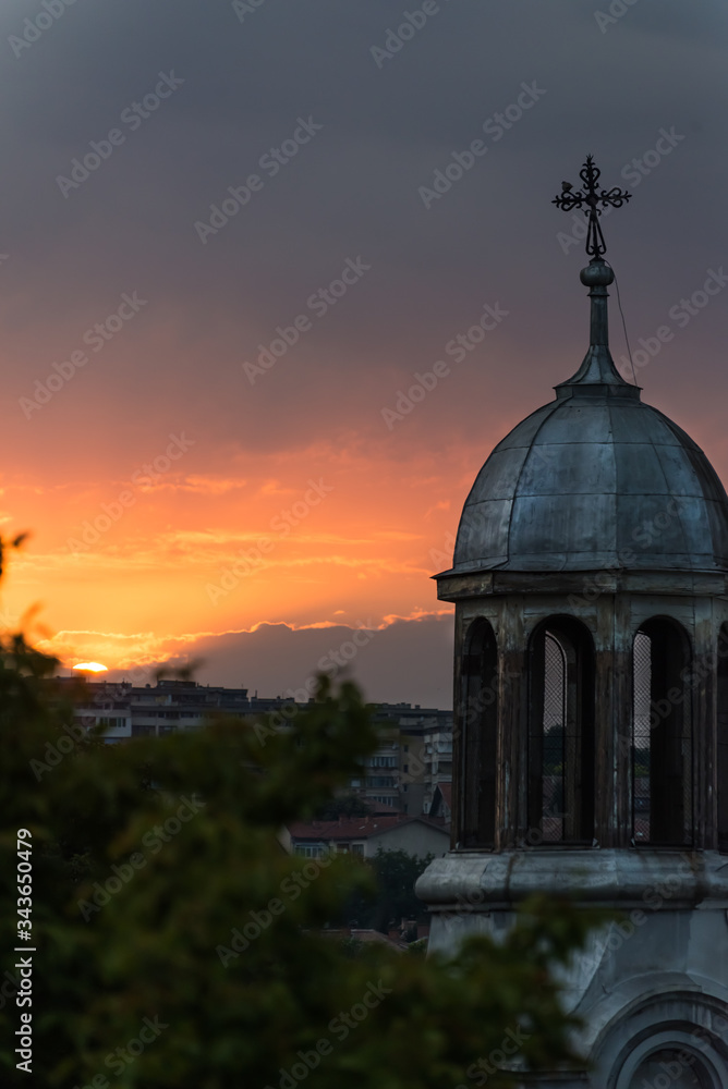 Red/ orange sunset over a town and orthodox church
