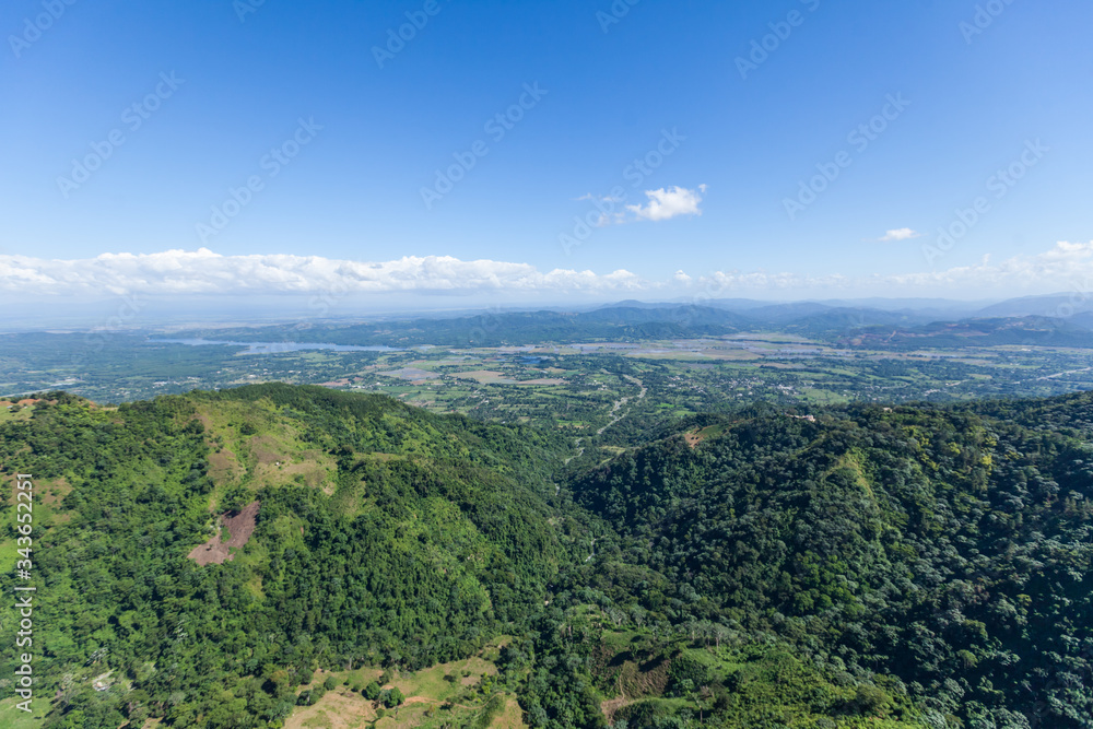 Mountain view from above on green mountains hills meadows and blue sky. Green landscape aerial drone view on the forest  