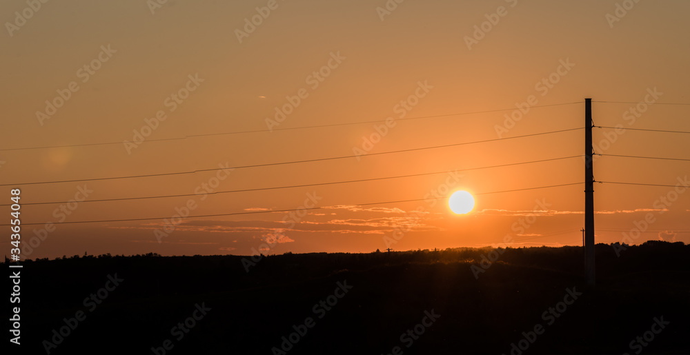 Power lines pole silhouette at sunset. High voltage wires carrying electricity. Energy and power generation concept