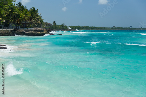 Fototapeta Naklejka Na Ścianę i Meble -  Beach landscape with sand, white foam waves, palm trees, blue sky, turquoise water and clouds, paradise Caribbean coast of Dominican republic 