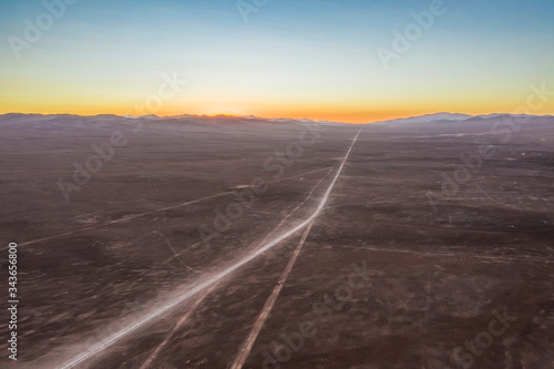 Exploring Atacama Desert vast dry extensions in the driest area of this amazing desert on an infinite dirt road. An awe road trip adventure crossing the infinite sand extensions from an aerial view 
