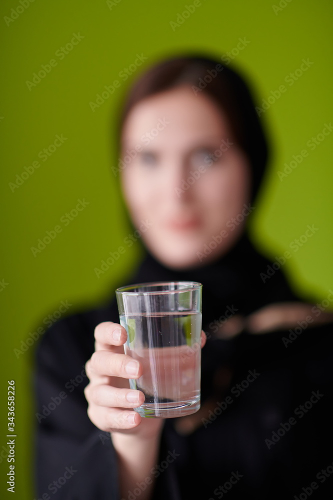 Woman in Abaya Holding a Date Fruit and glass of water Woman in Abaya Holding a Date Fruit and glass of water