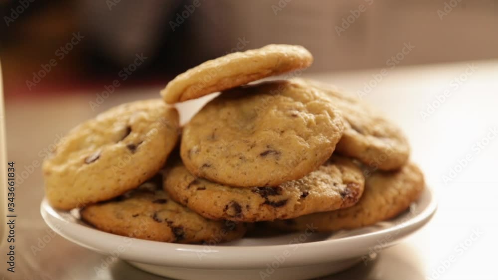 Close-up homemade chocolate chip cookies with a glass of milk on the kitchen table - children's snack - cookies with a glass of milk with a window behind in the afternoon Close-up homemade chocolate chip cookies with a glass of milk on the kitchen table - children's snack - cookies with a glass of milk with a window behind in the afternoon