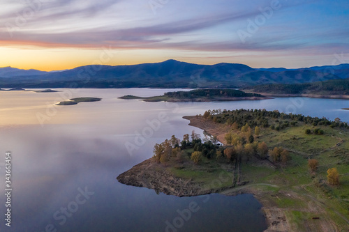 Fototapeta Naklejka Na Ścianę i Meble -  Aerial view of Gabriel y Galan lake at Extremadura countryside. An amazing view during sunset time on a cloudy day. The colors of the sky reflected over the lake waters give an idyllic landscape view
