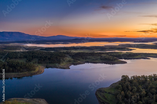Aerial view of Gabriel y Galan lake at Extremadura countryside. An amazing view during sunset time on a cloudy day. The colors of the sky reflected over the lake waters give an idyllic landscape view 