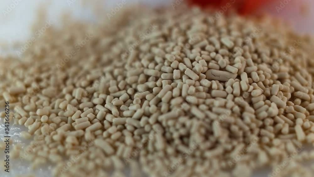 The pellets fall down in a heap. Granulated medical product, food additive, antibiotics, yeast, biologics. Extreme close-up, real time The pellets fall down in a heap. Granulated medical product, food additive, antibiotics, yeast, biologics. Extreme close-up, real time