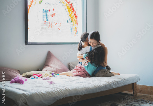 smileの虹が描かれた窓の前で母親に抱きつく姉妹 photo