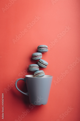 Five blue Macaroons and a blue cup laying on a red table 