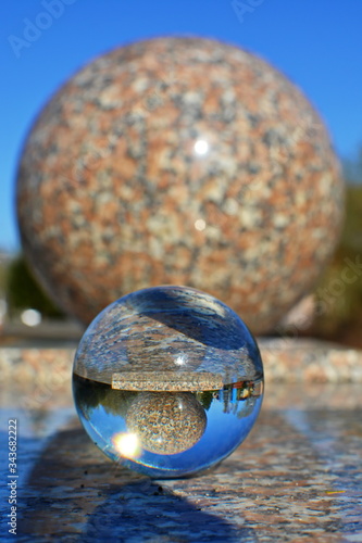 Transparent glass crystal ball on the marble surface with reflection marble sphere inside close up. Blurred background