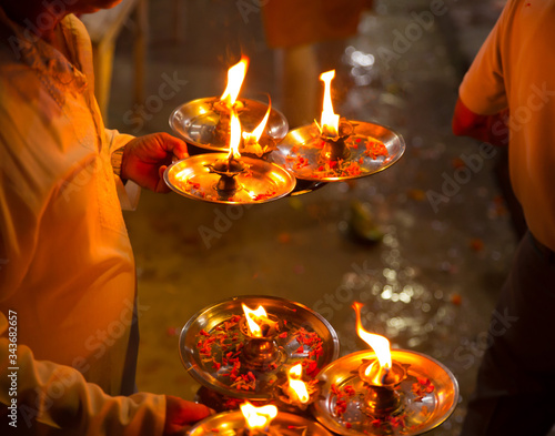 Foto A man holds several lightened oil diya lamps with flower petals in it for perfor