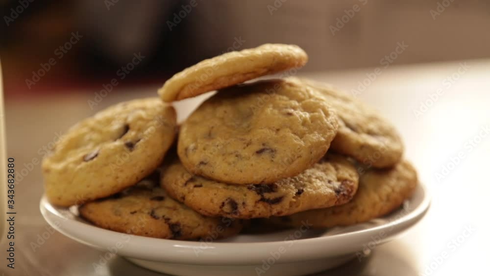 Close-up homemade chocolate chip cookies with a glass of milk on the kitchen table - children's snack - cookies with a glass of milk with a window behind in the afternoon Close-up homemade chocolate chip cookies with a glass of milk on the kitchen table - children's snack - cookies with a glass of milk with a window behind in the afternoon