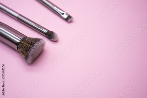 Professional makeup brushes with silver handle on pink background with copy space. Concept for beauty and face cosmetic
