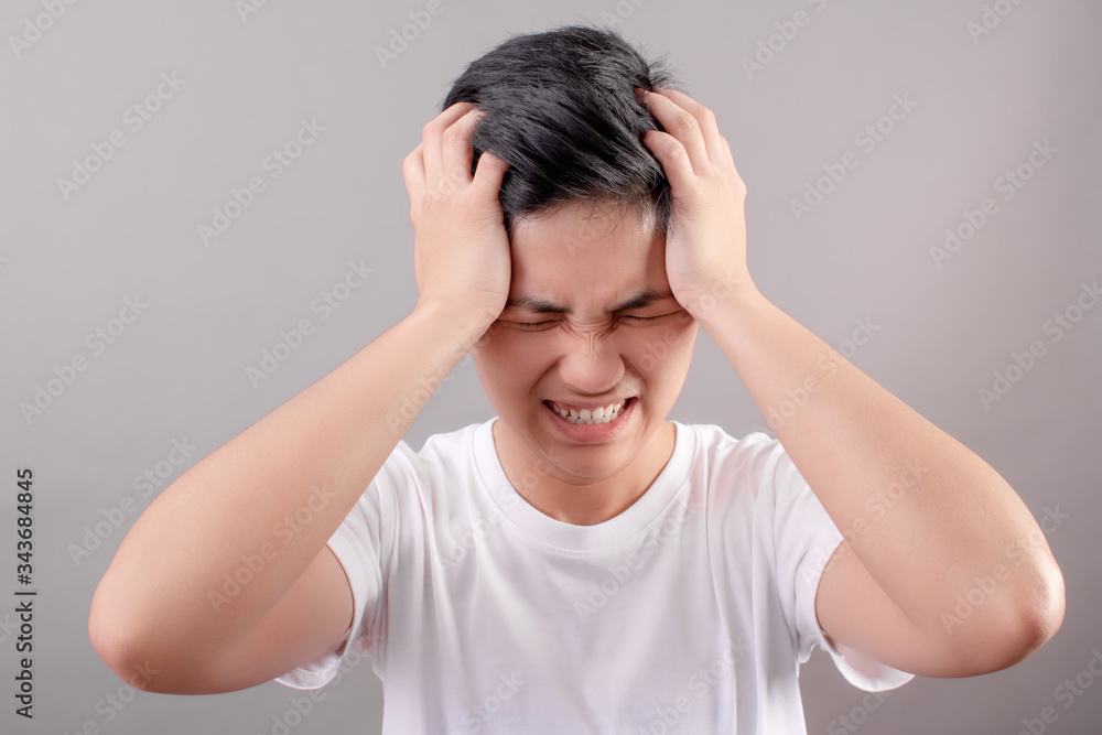 Asian people are upset and squeezing their heads with hands from a headache. The concept of stress and migraine. Asian people are upset and squeezing their heads with hands from a headache. The concept of stress and migraine.