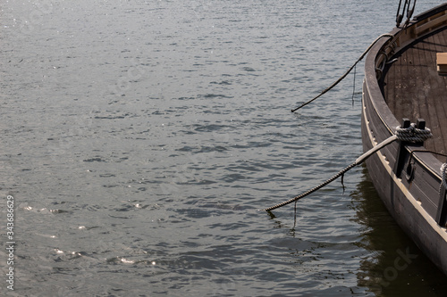 Open water copy space, edge of old wooden boat hull with ropes leading into the water, horizontal aspect