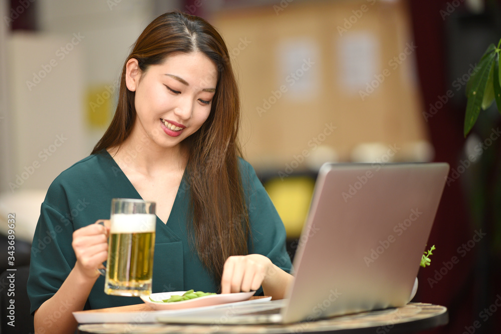 PCを見ながらお酒を飲む女性 PCを見ながらお酒を飲む女性