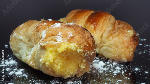 Close-up delicious cannoncini or puffs pastry horns filled with custard. Traditional Italian food pastry. Black background