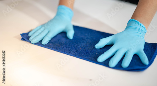 Male hand wear surgical glove while rubbing with the cloth  for cleaning and sweeping dust on the steel board.