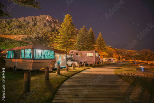 Caravans and mobile homes of holidaymakers under stary sky along wooden walkway to base of Mount Maunganui photo