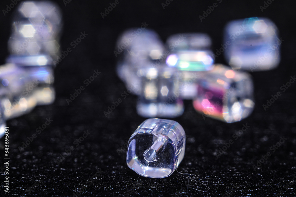blue square beads on a black background in low key with a boke in the background
blue square beads on a black background in low key with a boke in the background