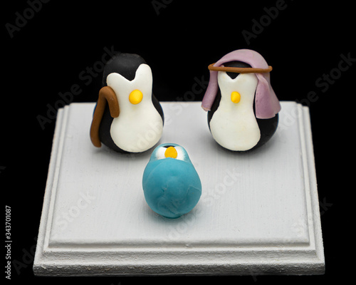 handmade figurines of Joseph, Mary, and Jesus in penguin form on black background photo