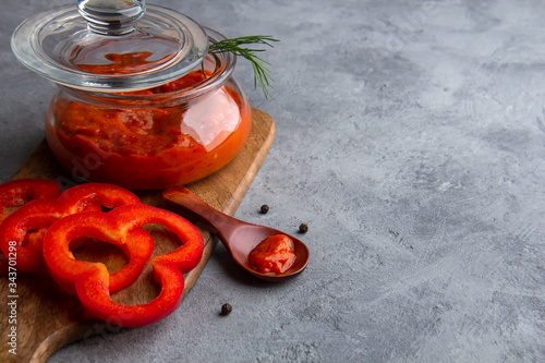 Glass jar with ajvar, lutenitza on a gray background photo