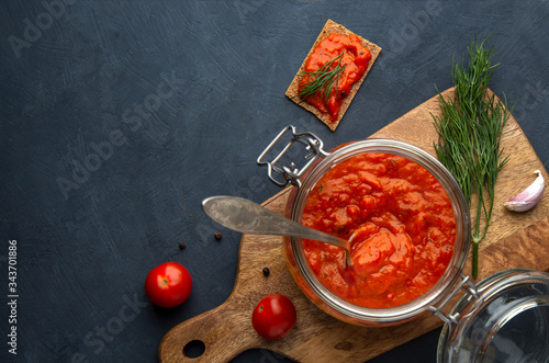 Ajvar, pinjur, lutenitsa, harissa in the bank on a dark background