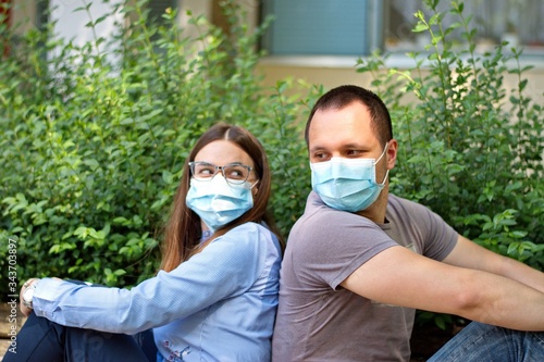 Young couple wearing protective medicine mask sitting on bench