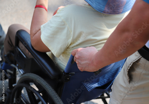 Closeup of man's hand assisting elderly woman in wheelchair.