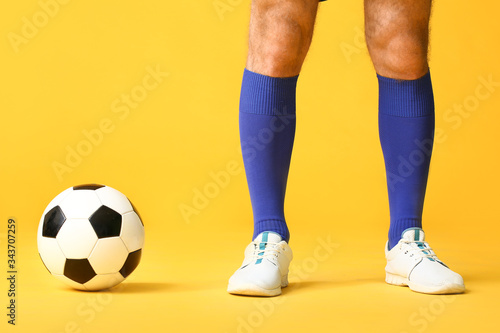 Legs of male football player on color background