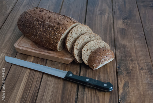 loaf of black bread with a knife on a wooden board