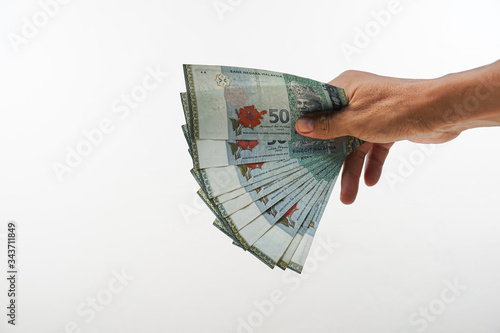 Malay hand holding Malaysia ringgit on white background. 