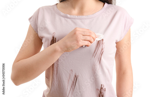 Young woman wiping stains from dirty clothes against white background