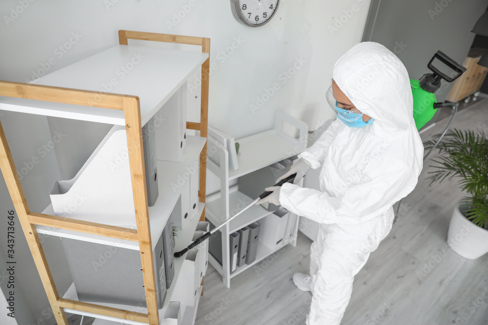 Worker in biohazard suit disinfecting office Worker in biohazard suit disinfecting office