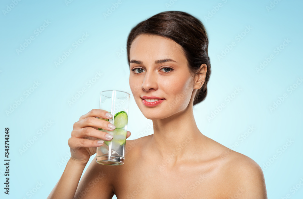 beauty and detox concept - woman drinking fresh water with cucumber and ice over blue background beauty and detox concept - woman drinking fresh water with cucumber and ice over blue background
