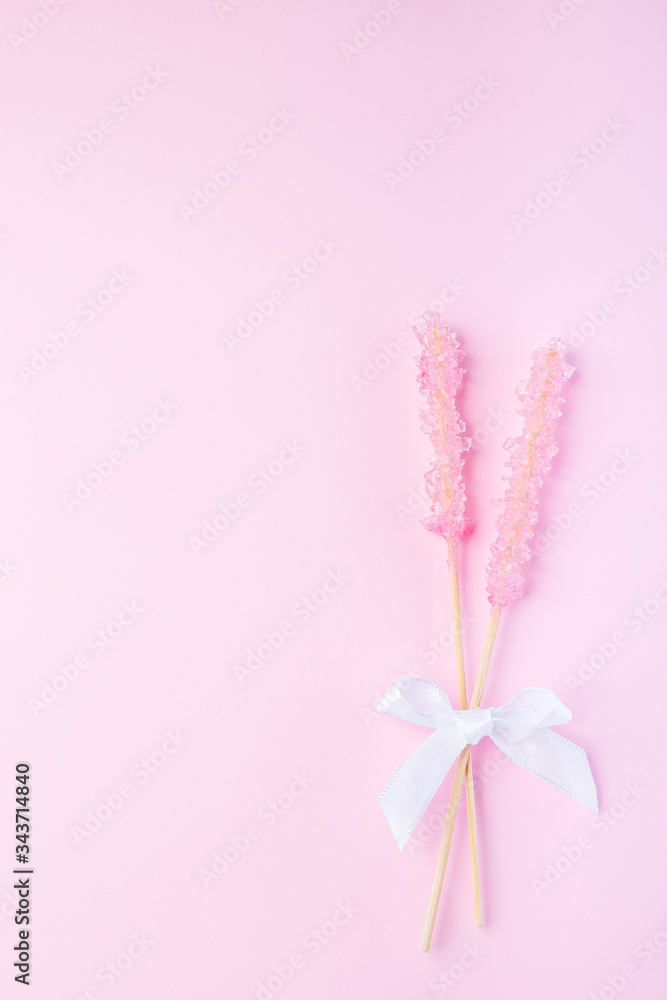 Rock candy on pink paper background decorated with a white bow, vertical, top view, copy space Rock candy on pink paper background decorated with a white bow, vertical, top view, copy space