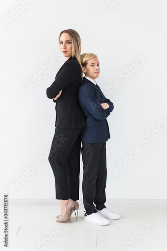 Teenager and single parent - Young mother and son standing together, back to back on white background.