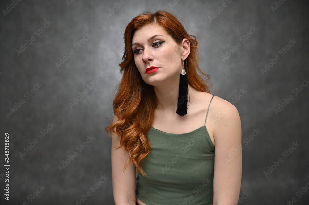 Portrait on a gray background of a pretty red-haired young woman. A model with great makeup posing in a green t-shirt in the studio. Portrait on a gray background of a pretty red-haired young woman. A model with great makeup posing in a green t-shirt in the studio.