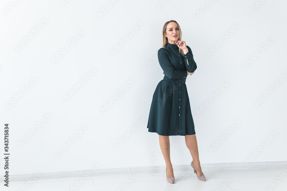 Fashionable young blonde woman in beautiful elegant dress posing at white studio with copy space. Fashionable young blonde woman in beautiful elegant dress posing at white studio with copy space.